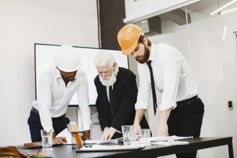 Businessman And Architects Looking At Blueprints In An Office