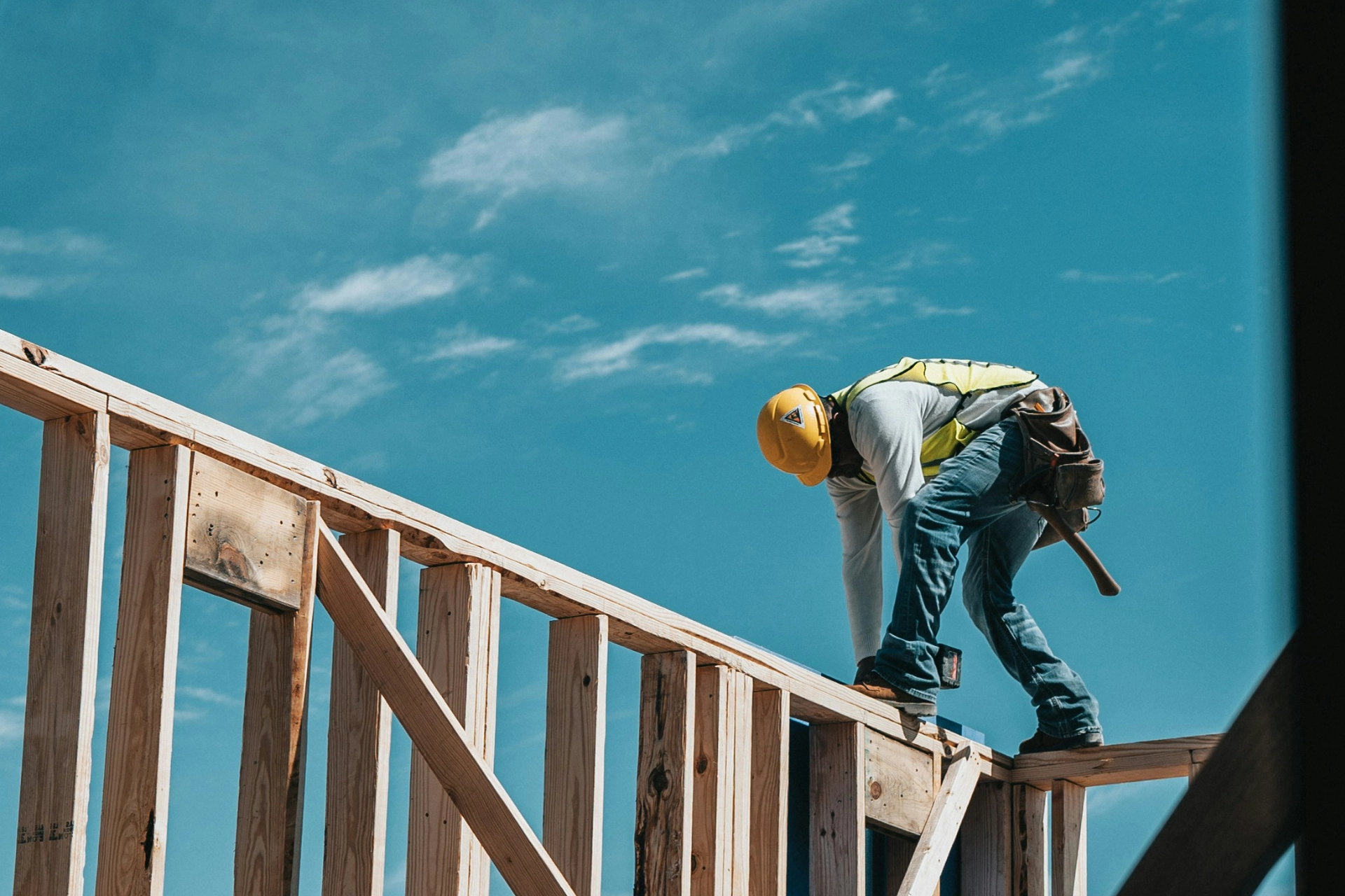 Man In Construction Uniform Working On Top Of Wooden Pillars